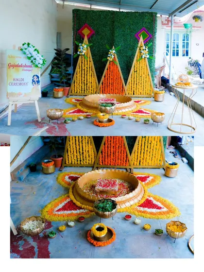 A detailed shot of the Haldi ceremony decor. The vibrant marigold and rose petal rangoli and the traditional brass vessels create a beautiful and festive setup.