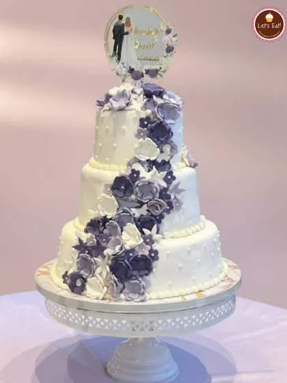 This three-tiered wedding cake was a dream to create. Adorned with a cascade of hand-made purple sugar flowers, it’s a perfect example of how I craft elegant centerpieces for your biggest moments. Each tier can be a different flavor to delight all your guests.