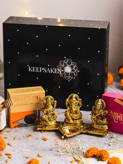 The "Diya" hamper is a complete festive package. It includes a beautiful brass Ganesha, Lakshmi, and Saraswati idol set, premium honey, and gourmet sweets, all presented in my signature black keepsake box.