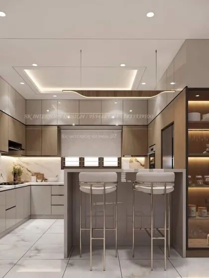 Here is a perfect example of a modern, open-concept kitchen. We designed this U-shaped layout with a breakfast counter, combining glossy beige and wood-finish cabinets with a sleek black countertop and integrated appliances for a seamless look.