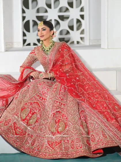 A majestic pose on the stairs, showing off the full glory of her red bridal lehenga. This is the kind of look that makes a grand entrance unforgettable.