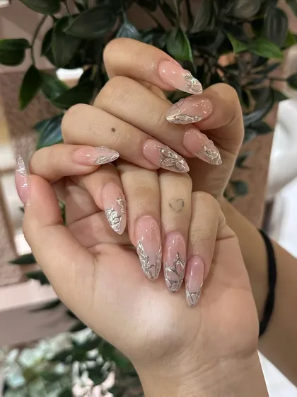 A full view of the metallic silver leaf nail art on long, elegant extensions. This is a perfect example of our detailed, high-impact designs.