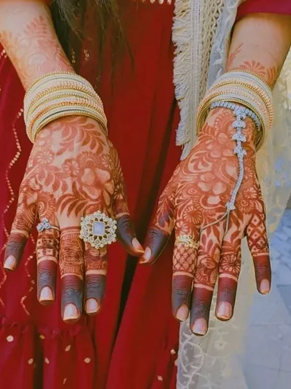A stunning photo of a bride's hands, showcasing the rich henna stain complemented by her beautiful rings and bangles. This is what it's all about.