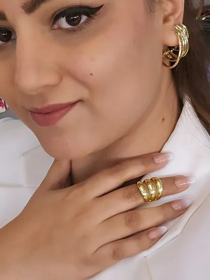 A close-up of our chunky gold-tone ring and matching hoop earrings. This set is perfect for creating a powerful, coordinated look that's both modern and timeless.