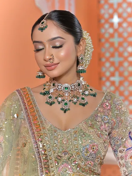Another beautiful close-up, this time with a softer expression. It provides a clear view of the choker necklace and the intricate details of the green gemstones.