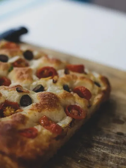 A close-up of a beautiful focaccia bread, studded with tomatoes and olives. A favorite in our Italian classes.