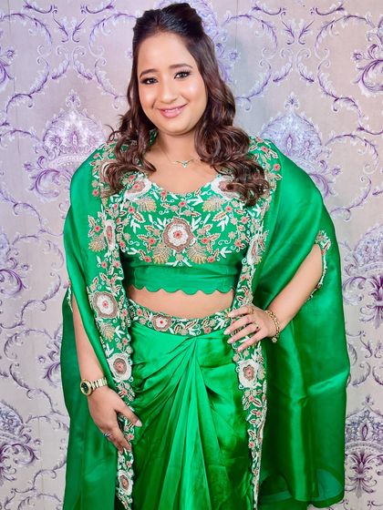 A smiling portrait of our client in her vibrant green saree, looking confident and beautiful.