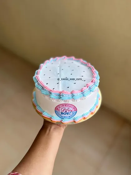 A classic gender reveal cake with pink and blue piping. The "Girl or Boy?" sticker adds to the anticipation.