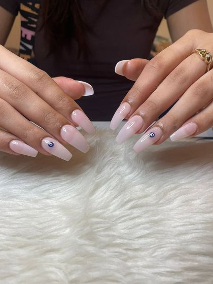 A simple yet protective design featuring a soft pink base on long coffin nails with a single evil eye charm on each hand.
