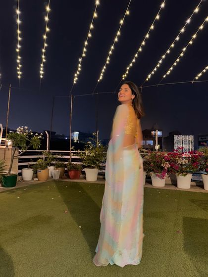 A candid twirl on the terrace during Diwali. The fairy lights create a magical backdrop, and the lightweight organza of the saree moves beautifully.