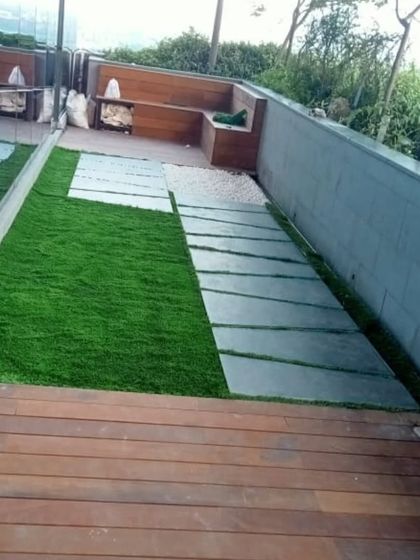 A combination of wooden decking, artificial grass, and stone pavers creates a multi-textured and visually interesting ground surface.