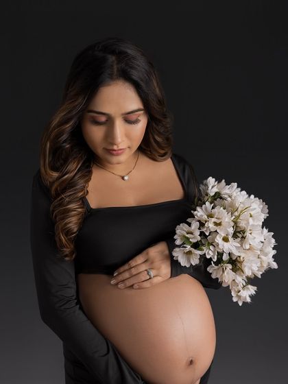 A classic and elegant portrait in a simple black gown, holding a bouquet of white flowers for a beautiful contrast.