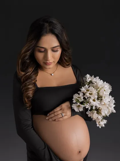A classic and elegant portrait in a simple black gown, holding a bouquet of white flowers for a beautiful contrast.