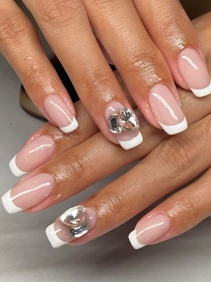 A classic French manicure on square nails, made special with large silver heart charms. This shows how to use statement charms effectively.