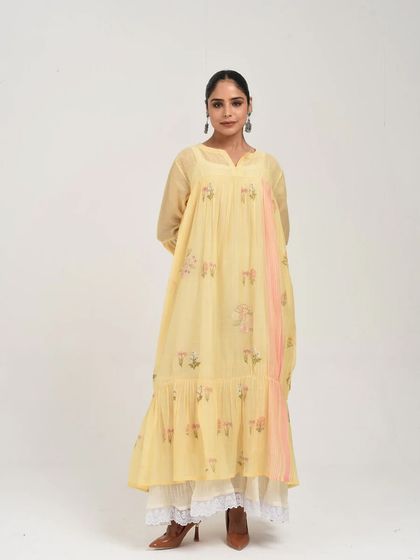 A full view of the yellow tiered dress, layered over a white lace skirt for a touch of vintage charm.