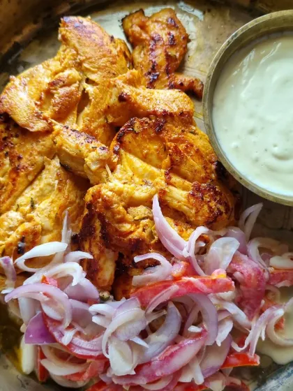 A plate of grilled chicken with a side of fresh onion salad and a creamy dip. This is how you eat to nourish your body.