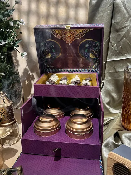 A majestic two-tiered purple box with a peacock design. The top layer holds sweets, while the bottom drawer contains beautiful copper-lidded jars.