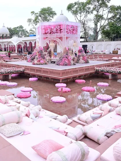 The mandap was set on a platform over water, with floating floral arrangements and relaxed floor seating for guests, creating a serene and immersive experience.