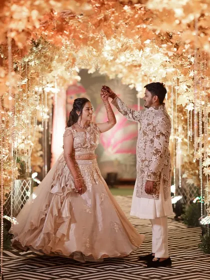 A romantic twirl under a golden foliage archway. The entrance to their reception was designed to be a magical experience from the very first step.