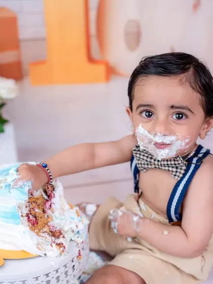 Getting hands-on with the birthday cake. This action shot captures the sensory experience and excitement of a first cake smash.