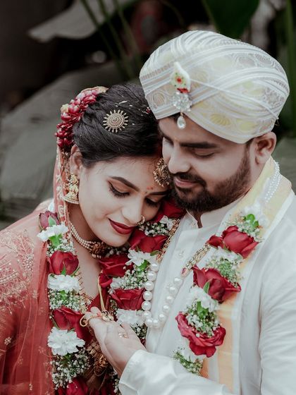 A slightly wider version of the previous shot, showing more of their wedding attire and the beautiful floral garlands.