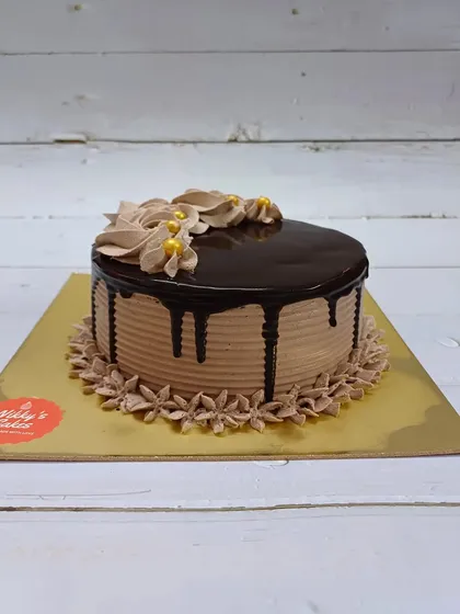 This is my classic eggless chocolate truffle cake. It features a simple yet elegant design with a smooth ganache glaze, a chocolate drip, and delicate frosting swirls, perfect for any occasion.