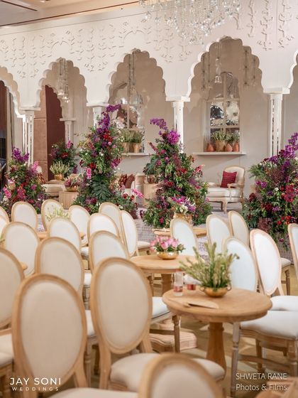 A wider view of the seating arrangement, set against a backdrop of grand white arches and lush floral towers, creating a stunning visual for the wedding ceremony.