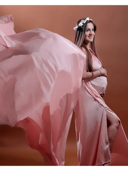 A beautiful studio shot capturing the movement of a light pink gown, with the mother-to-be wearing a delicate floral crown.