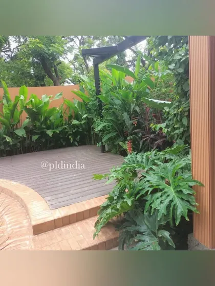 A deck area in a Juhu garden, surrounded by dense tropical planting. This space is perfect for outdoor dining or lounging, offering privacy and a beautiful green view.