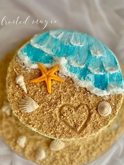 I love creating textures that you can almost feel, like the edible sand on this beach-themed cake. The gentle buttercream waves, hand-moulded shells, and a little heart drawn in the "sand" make this a perfect cake for anyone who loves the ocean.