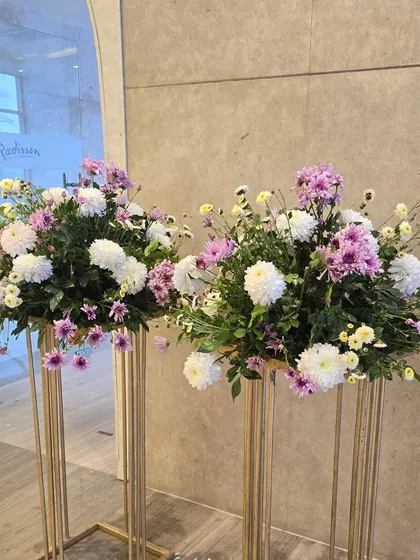 Beautiful fresh flower arrangements on tall gold stands, perfect for placing at an entrance or around the venue.