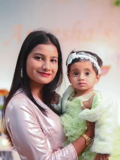 A mother and daughter moment during a Jungle Safari themed first birthday party. The soft lighting and pastel-colored animal cutouts create a gentle and sweet version of the jungle theme.