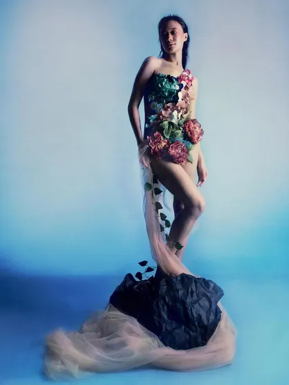 Ophelia stands on a rock, reminiscent of classical statues. This pose, combined with the flowing tulle and floral bodysuit, portrays her as a figure of enduring strength and beauty.