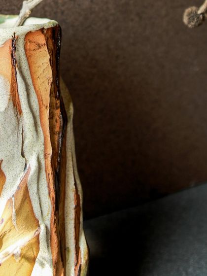 A close up of a Kurinuki vase, showing the chiseled, mountain like facade and the interplay of slips and glazes.