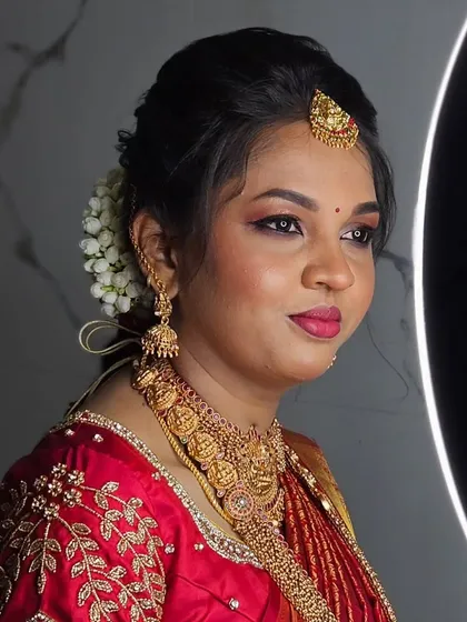A radiant muhurtham makeover. The focus here is on creating a flawless base that lasts all day, paired with beautifully defined eyes and lips that complement the traditional red saree.
