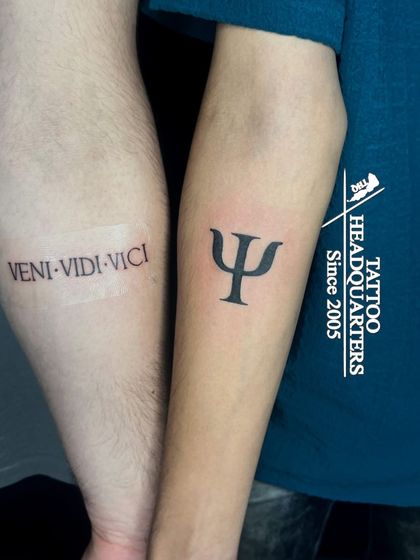 A pair of tattoos: one with the Latin phrase "VENI VIDI VICI" and the other with the Greek Psi symbol for psychology.