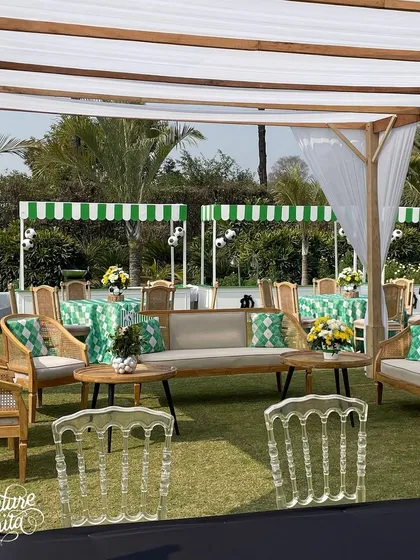 A lounge area for the golf party with green and white patterned cushions and transparent ghost chairs.