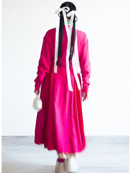 The back view, showing the long braided hairstyle tied with white ribbons, which added a playful, almost girlish touch to the sophisticated outfit.