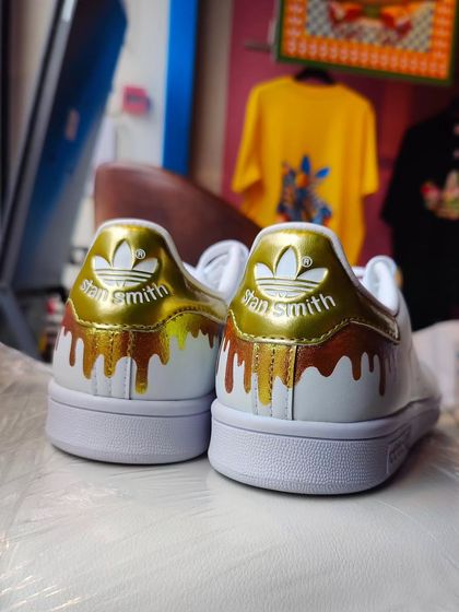 A pair of Stan Smiths with a custom gold drip effect on the heel, painted during my live event at the Adidas store in Bangalore. It's a subtle but stylish way to personalize a classic shoe.