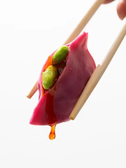 A minimalist, high-impact shot of a single dim sum dripping with sauce. This macro style focuses on texture and detail, creating a powerful craving.