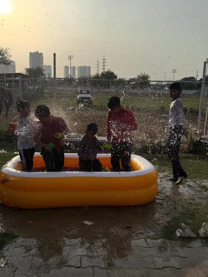 Kids splashing in an inflatable pool at sunset during a Holi party. It's a fantastic way to cool down and have fun.