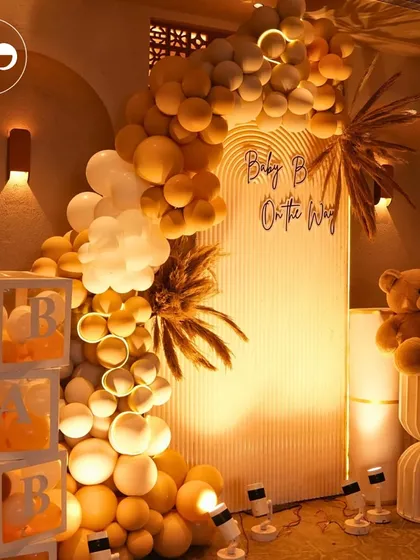 A warm and inviting boho-themed baby shower setup. The neutral-toned balloon arch, pampas grass, and 'BABY' blocks create a chic and cozy atmosphere.