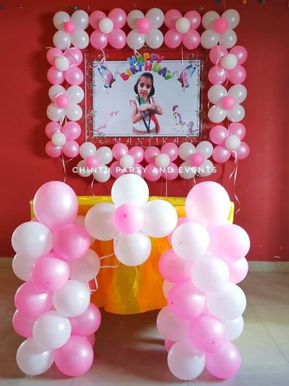 A simple and sweet balloon decoration for a kid's birthday party at home. The setup features a photo frame made of pink and white balloons.