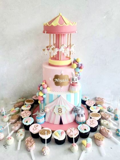 A carnival-themed dessert table is always so much fun. The centerpiece is a two-tiered cake with a working carousel on top, surrounded by colourful cupcakes, cake pops, and other treats.