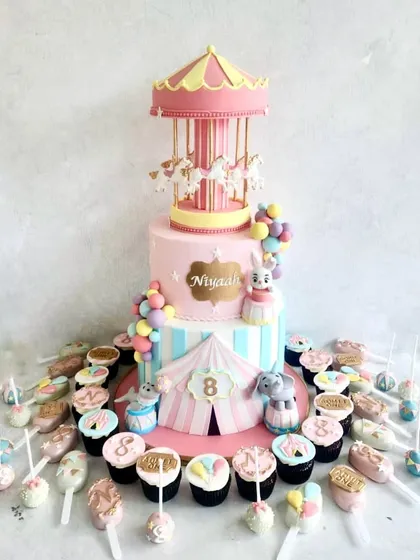 A carnival-themed dessert table is always so much fun. The centerpiece is a two-tiered cake with a working carousel on top, surrounded by colourful cupcakes, cake pops, and other treats.