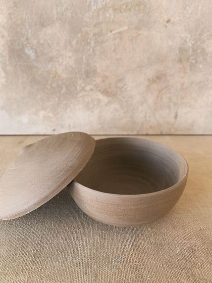 A beautiful, raw lidded jar made by one of our students. The beauty of this unglazed piece is in its simplicity and the texture of the natural clay, showing the marks of the maker's hands.