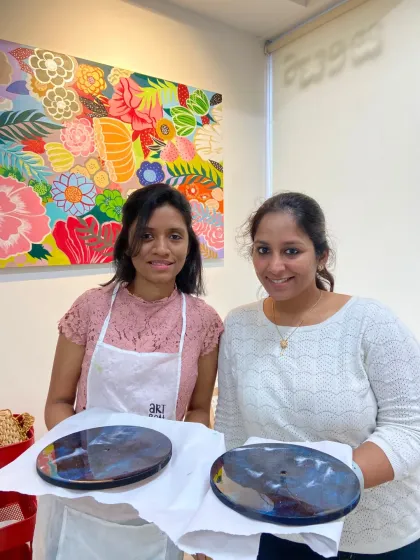 Two participants holding up their newly created resin clocks. The glossy finish and unique patterns make for a stunning piece of home decor.