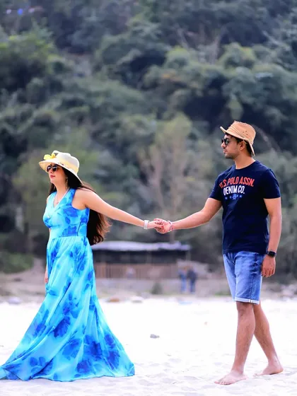 A casual and fun pre-wedding moment captured on a sandy riverbank. The couple's relaxed outfits and hand-in-hand walk create a feeling of easy, natural romance.