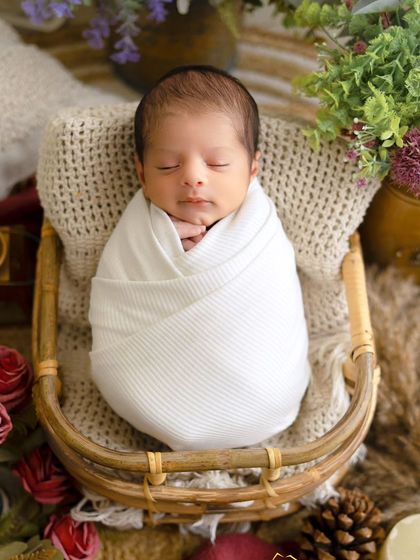 A perfect little bundle wrapped in white. This classic newborn pose in a rustic basket highlights the baby's peaceful and serene nature.