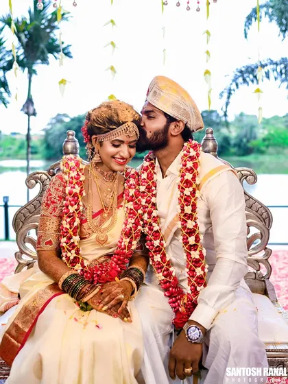 An intimate and tender moment during a traditional South Indian wedding ceremony. The groom's gentle kiss on the bride's forehead captures the pure emotion of the day.